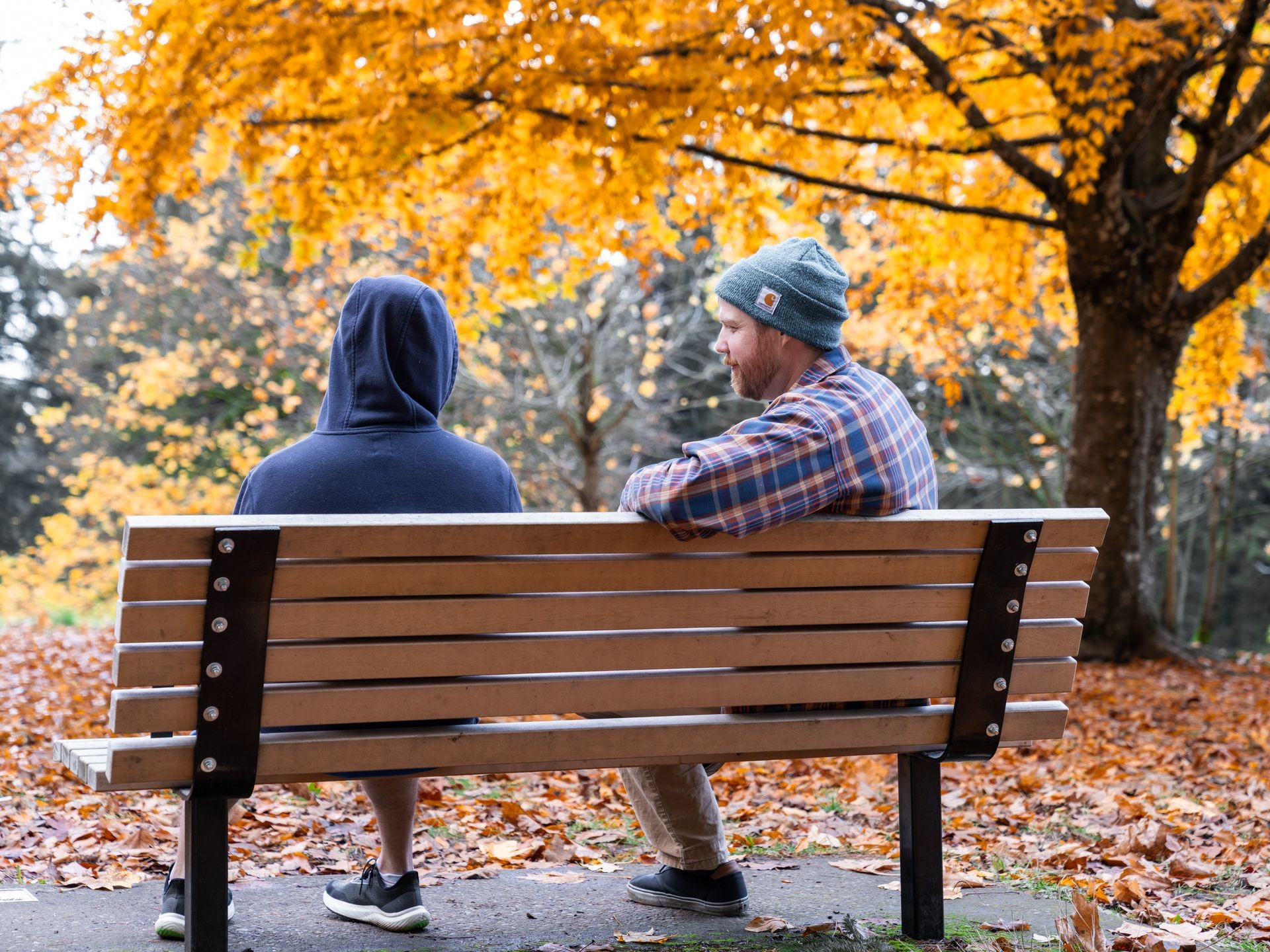 men sitting on bench park in fall